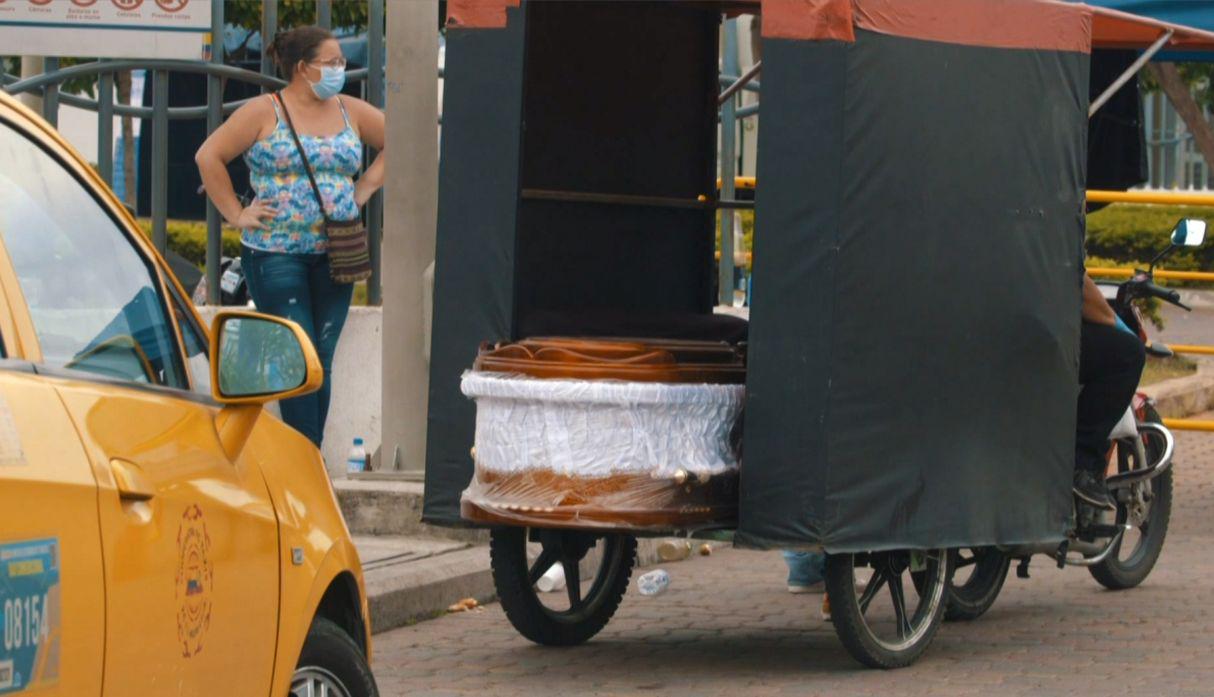 A video grab from AFP TV shows a wrapped coffin on the back of a motorcycle taxi outside of a hospital in Guayaquil, Ecuador, on April 1, 2020. - Residents of Guayaquil, in Ecuador's southwest, express outrage over the way the government has responded to the numerous deaths related to the novel coronavirus, COVID-19, saying there are many more deaths than are being reported and that bodies are being left in homes for days without being picked up. (Photo by Enrique ORTIZ / AFPTV / AFP)