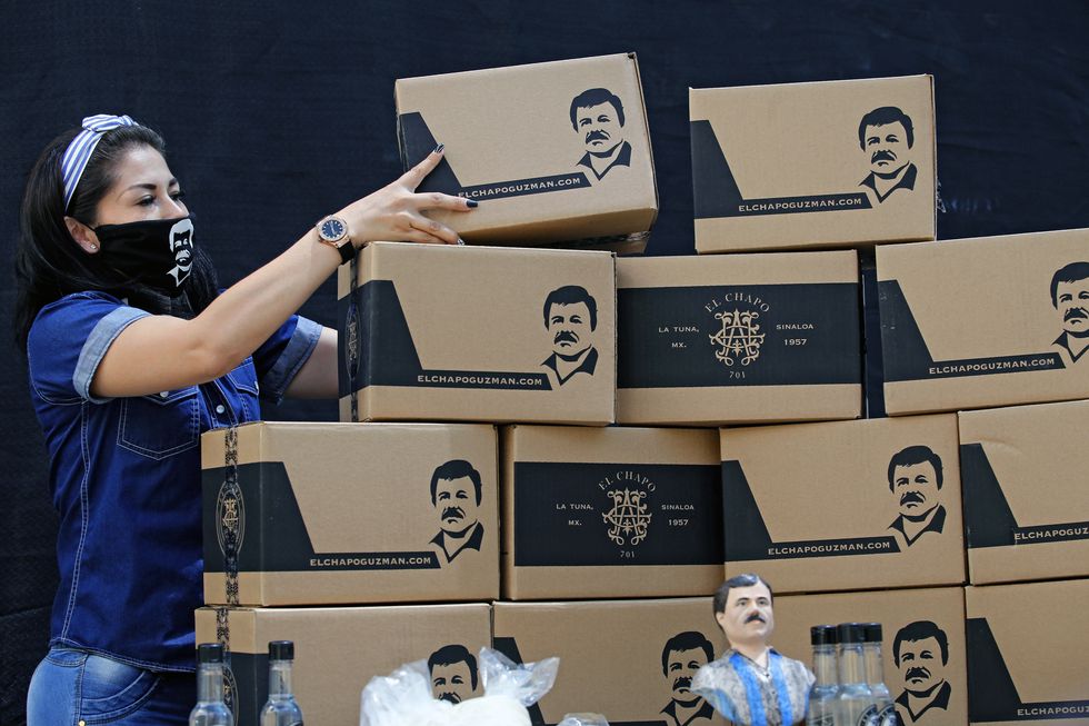 An employee of the Alejandrina Guzman Foundation wears a face mask with the image of Mexican drug lord Joaquin "El Chapo" Guzman -Alejandrina's father- as she arranges boxes with basic goods to be donated to people in need amid the new coronavirus pandemic in Guadalajara, Mexico, on April 17, 2020. (Photo by Ulises Ruiz / AFP)