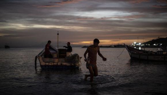Los pescadores regresan durante el atardecer después de un día de pesca en una playa en el pueblo pesquero Juangriego de Isla de Margarita, estado Nueva Esparta, Venezuela, el 24 de noviembre de 2022. (Foto de Yuri CORTEZ / AFP)