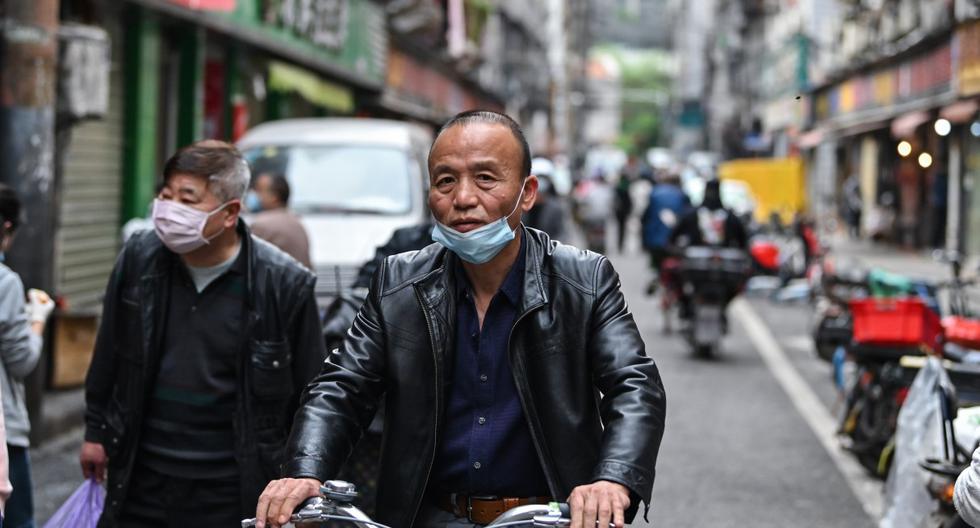 Un hombre portando una máscara facial monta una bicicleta en una calle de Wuhan, en la provincia central china de Hubei. (Archivo / Hector RETAMAL / AFP)