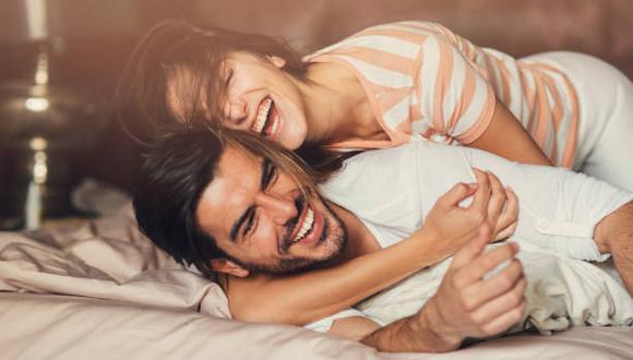 Happy young playful couple in bed.