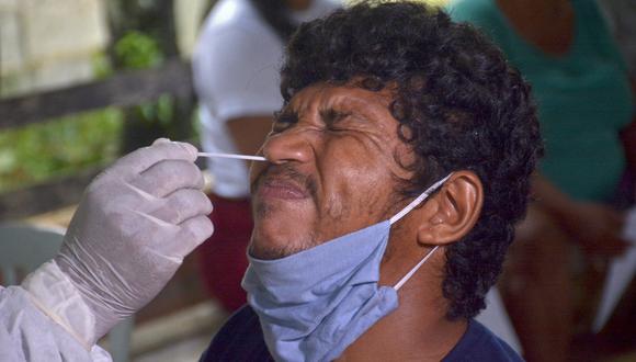 Un trabajador de la salud toma una muestra de hisopo a un residente de la comunidad ribereña de Bela Vista do Jaraqui, Manaos, estado de Amazonas, Brasil, el 18 de enero de 2021. (Foto: MARCIO JAMES / AFP)