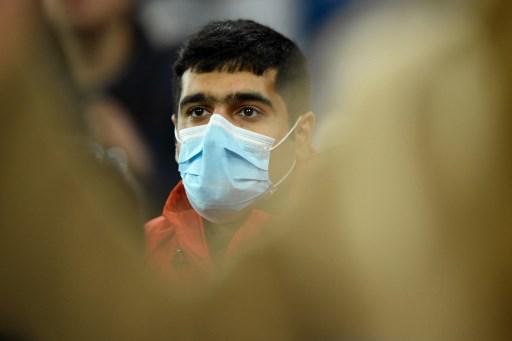 A fan wearing a protective mask in light of the coronavirus outbreak attends the UEFA Champions League round of 16 first-leg football match between Real Madrid CF and Manchester City at the Santiago Bernabeu stadium in Madrid on February 26, 2020. (Photo by OSCAR DEL POZO / AFP)