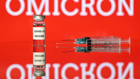 Una imagen de ilustración tomada en Londres el 2 de diciembre de 2021 muestra un vial con la etiqueta adhesiva de la vacuna Covid-19 adjunta, junto a las jeringas y una pantalla con la palabra 'Omicron' (Foto: Justin Tallis / AFP)