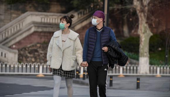 Esta foto muestra a dos personas caminando por una calle en Wuhan y usando mascarillas como medida preventiva contra el coronavirus COVID-19. China reportó solo ocho casos del brote de coronavirus COVID-19, sin nuevas infecciones domésticas fuera del epicentro de la provincia de Hubei. (AFP)