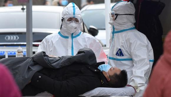Medical workers wearing protective suits as a precaution against the COVID-19 coronavirus deliver a patient to the fever clinic at a hospital in Beijing on January 13, 2021. / AFP / GREG BAKER

