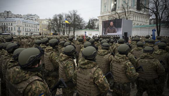 Militares y mujeres militares ucranianos que asisten a una ceremonia con el presidente ucraniano Volodymyr Zelensky en una pantalla en la Plaza de Santa Sofía en Kiev, en el primer aniversario de la invasión rusa de Ucrania. (Foto de Handout / SERVICIO DE PRENSA PRESIDENCIAL DE UCRANIA / AFP)