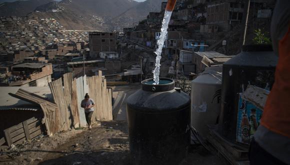 Los tambores se llenan con agua potable de un camión cisterna en Pamplona Alta, en las afueras del sur de Lima, el 22 de marzo de 2022. (Foto de Ernesto BENAVIDES / AFP)