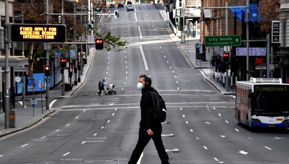 Un hombre camina por la carretera principal en el distrito comercial central de Sídney el 26 de junio de 2021. (Saeed KHAN / AFP).