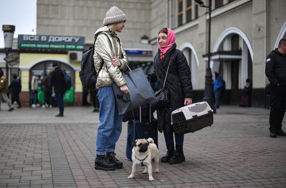 Dos mujeres hablan mientras están de pie con maletas y animales cerca de la estación de tren Kyiv-Pasazhyrskyi en Kiev en la mañana del 24 de febrero de 2022. (Foto: Daniel LEAL / AFP)