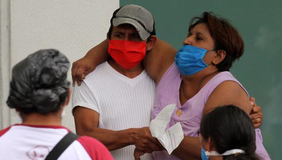 A man helps a sick woman enter a hospital in Guayaquil, Ecuador on April 1, 2020. - Residents of Guayaquil, in Ecuador's southwest, express outrage over the way the government has responded to the numerous deaths related to the novel coronavirus, COVID-19, saying there are many more deaths than are being reported and that bodies are being left in homes for days without being picked up. Ecuador marked its highest daily increase in deaths and new cases of coronavirus on Sunday, with the total reaching 14 dead and 789 infected, authorities had said. (Photo by Enrique Ortiz / AFP)