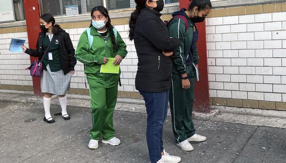 Una adolescente se para junto a su madre mientras espera para ingresar a la escuela en la Ciudad de México el 10 de enero de 2022.  (Foto por ALFREDO ESTRELLA / AFP)