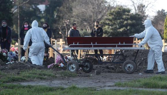 Empleados del cementerio de Flores trasladan un ataúd bajo los protocolos instaurados debido a la pandemia por COVID-19. (EFE/Juan Ignacio Roncoroni).