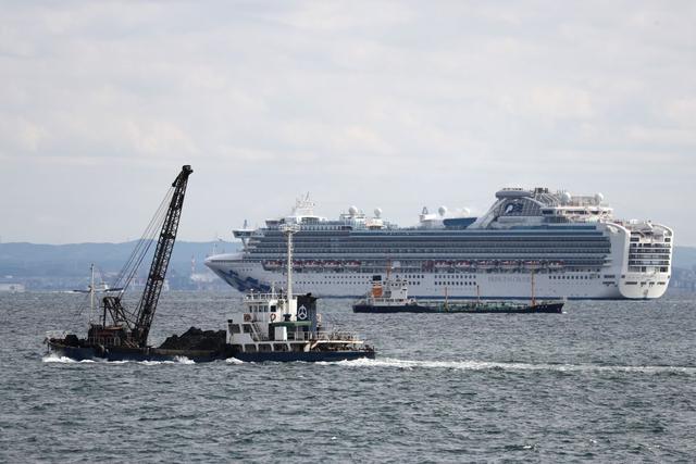 Un grupo de barcos pasan junto al crucero Diamond Princess con más de 3.000 personas, ya que se encuentra anclado en cuarentena frente al puerto de Yokohama. (AFP)