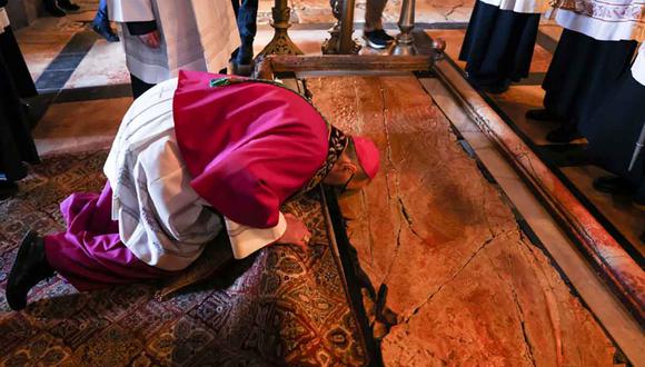 The head of the Roman Catholic Church in the Holy Land, Apostolic Administrator of the Latin Patriarchate Pierbattista Pizaballa kneels by the Unction Stone, believed to be the place where Christ' body was laid down after being removed from the crucifix and prepared for burial, at the Church of the Holy Sepulchre in the Old City of Jerusalem, on Palm Sunday, on April 10, 2022. - The ceremony is a landmark in the Roman Catholic calendar, marking the triumphant return of Christ to Jerusalem the week before his death, when a cheering crowd greeted him waving palm leaves. Palm Sunday marks the start of the most solemn week in the Christian calendar. (Photo by AHMAD GHARABLI / AFP)