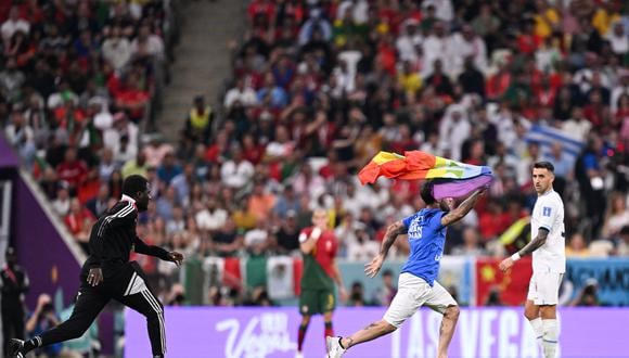Un guardia de seguridad intenta bloquear a un hombre que invade la cancha con una bandera LGBT y usa una camiseta que dice "Respeto a la mujer iraní" durante el partido de fútbol del Grupo H de la Copa Mundial Qatar 2022 entre Portugal y Uruguay en el Estadio Lusail en Lusail. , al norte de Doha el 28 de noviembre de 2022. (Foto de Kirill KUDRYAVTSEV / AFP)
