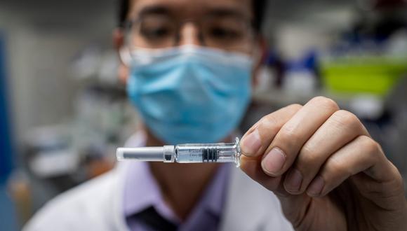 (FILES) This file photo taken on April 29, 2020 shows an engineer displaying an experimental vaccine for the COVID-19 coronavirus that was tested at the Quality Control Laboratory at the Sinovac Biotech facilities in Beijing. - China has mobilised its army and fast-tracked tests in the global race to find a coronavirus vaccine, and is involved in several of the dozen or so international clinical trials currently under way. (Photo by NICOLAS ASFOURI / AFP) / TO GO WITH Health-virus-China-vaccines,FOCUS by Ludovic EHRET