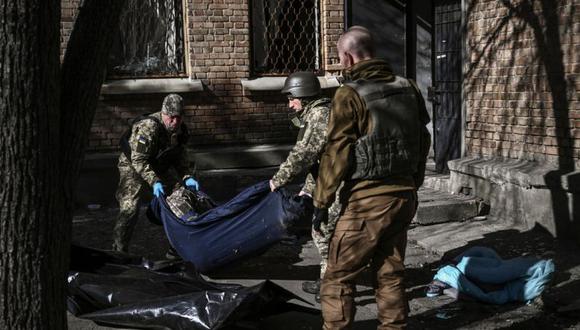 Miembros del servicio militar de emergencia retiran el cuerpo de un militar ucraniano muerto en el área de un instituto de investigación, parte de la Academia Nacional de Ciencias de Ucrania, después de un ataque, en el noroeste de Ucrania. (Foto: Aris Messinis / AFP).