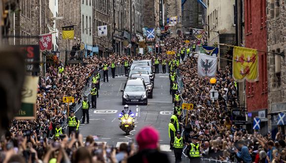 Los miembros del público se reúnen a lo largo de la Royal Mile para ver el coche fúnebre que lleva el ataúd de la reina Isabel II, mientras se conduce a través de Edimburgo hacia el Palacio de Holyroodhouse, el 11 de septiembre de 2022. (Foto de Jamie Williamson / PISCINA / AFP)