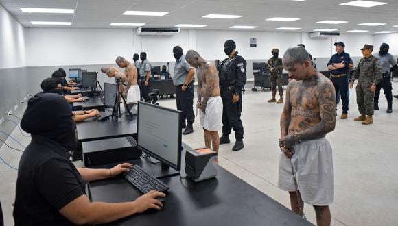 Policías registrando la llegada de internos de las pandillas MS-13 y 18 al nuevo penal "Centro de Confinamiento de Terroristas" (CECOT), en Tecoluca, 74 km al sureste de San Salvador, a 24 de febrero de 2023. (Foto de Presidencia salvadoreña / AFP)