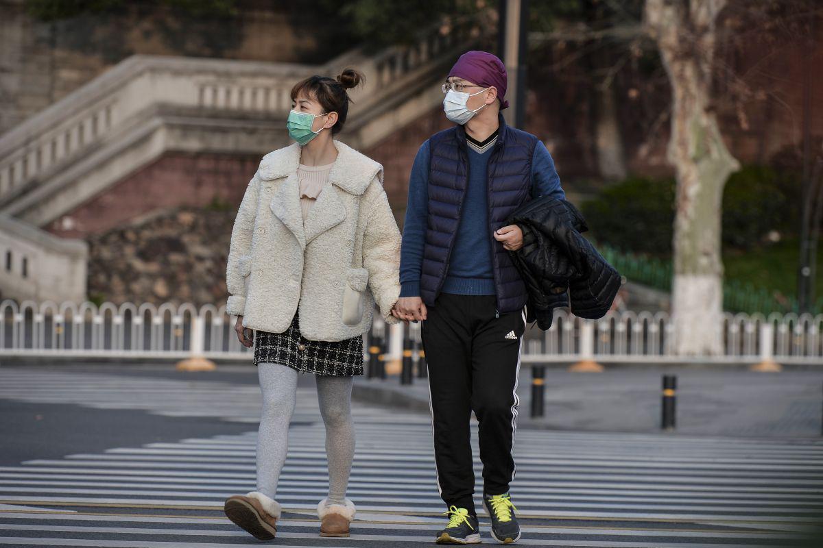 Esta foto muestra a dos personas caminando por una calle en Wuhan y usando mascarillas como medida preventiva contra el coronavirus COVID-19. China reportó solo ocho casos del brote de coronavirus COVID-19, sin nuevas infecciones domésticas fuera del epicentro de la provincia de Hubei. (AFP)