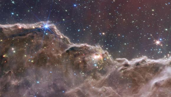 Una composición de la información capturada por la cámara de infrarrojo cercano (NIRCam) y el instrumento de infrarrojo medio (MIRI) en el telescopio espacial James Webb (JWST) que muestra un paisaje de montañas y valles  salpicados de estrellas brillantes que en realidad es el borde de una región cercana, joven, de formación estelar llamada NGC 3324 en la Nebulosa Carina. (Foto: Handout/NASA/AFP)