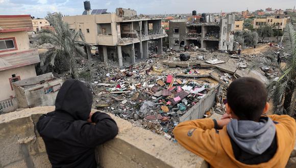 Niños palestinos observan a la gente parada entre los escombros de un edificio destruido durante los ataques israelíes en Rafah, en el sur de la Franja de Gaza. (Foto de Mohammed ABED / AFP)