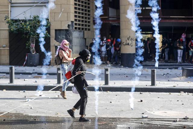 Un hombre libanés empapa un bote de gas lacrimógeno con agua durante los enfrentamientos con las fuerzas de seguridad en el centro de Beirut. (AFP / JOSEPH EID).