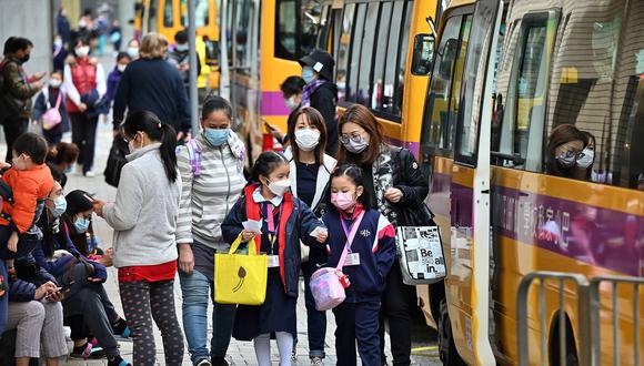 Los niños son escoltados desde la escuela en Hong Kong el 11 de enero de 2022, cuando la ciudad anunció la suspensión de todas las escuelas primarias y de jardín de infantes hasta después del Año Nuevo Lunar a principios de febrero, luego de un brote de coronavirus variante de Omicron. (Foto de Peter PARQUES / AFP)
