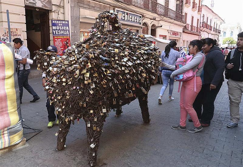 ​Cerdito de la fortuna atrae candados del amor puestos en puentes