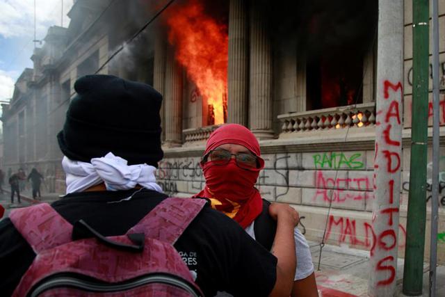 Cientos de manifestantes tomaron este sábado el Congreso de Guatemala y le prendieron fuego a varias oficinas hasta ser desalojados por fuerzas de seguridad y cuerpos de bomberos, que apagaron el incendio. (EFE/Esteban Biba)