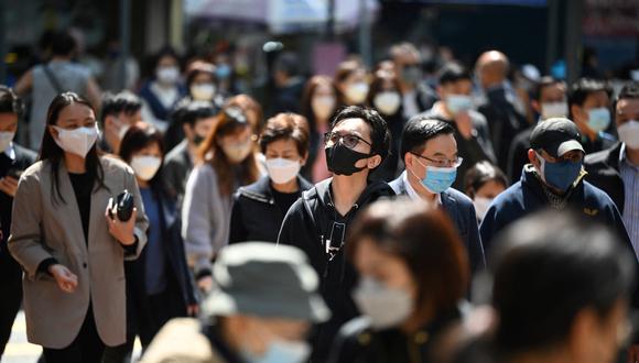 La gente usa máscaras en una calle de Hong Kong el 27 de febrero de 2023 cuando los expertos en salud en el territorio respaldaron la extensión de su mandato de máscara hasta el 8 de marzo, dejando a Hong Kong como uno de los únicos lugares del mundo con tales reglas. (Foto de Peter PARQUES / AFP)