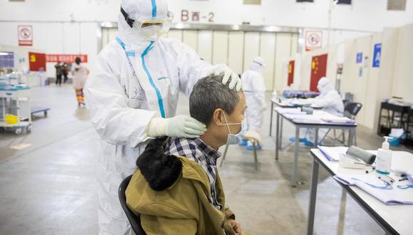 En la imagen se observa a un miembro del personal médico haciendo un masaje a un paciente que ha mostrado síntomas leves del coronavirus COVID-19 en un centro de exposiciones convertido en un hospital en Wuhan en la provincia central de Hubei, en China. (AFP)
