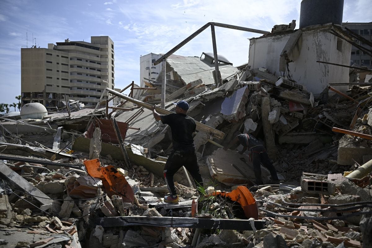 Unos hombres revisan los escombros de los edificios derrumbados mientras intentan recuperar sus pertenencias tras un terremoto en Catia La Mar, estado de La Guaira, a unos 30 km al noroeste de Caracas, el 25 de junio de 2026. Un terremoto doble, el más fuerte que ha sufrido Venezuela en más de un siglo, ha causado la muerte de al menos 164 personas y ha destruido varios edificios cerca de la capital, donde los residentes buscaban el 25 de junio a sus familiares desaparecidos. (Foto de Federico PARRA / AFP)