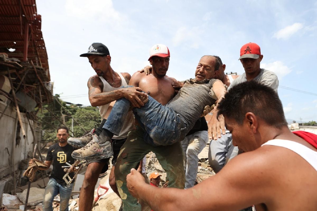 Personas en La Guaira, Venezuela, transportan a un hombre rescatado de entre los escombros de un edificio derrumbado un día después de que dos terremotos azotaran el país caribeño, el jueves 25 de junio de 2026. (Foto: AP/Pedro Mattey)