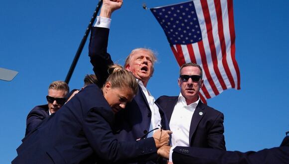 Ensangrentado, Donald Trump levanta el puño derecho y grita como señal de fuerza durante mitin en que sufrió atentado.