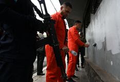 Obligan a que pandilleros -con grilletes y armas apuntándoles- borren grafitis en la calle