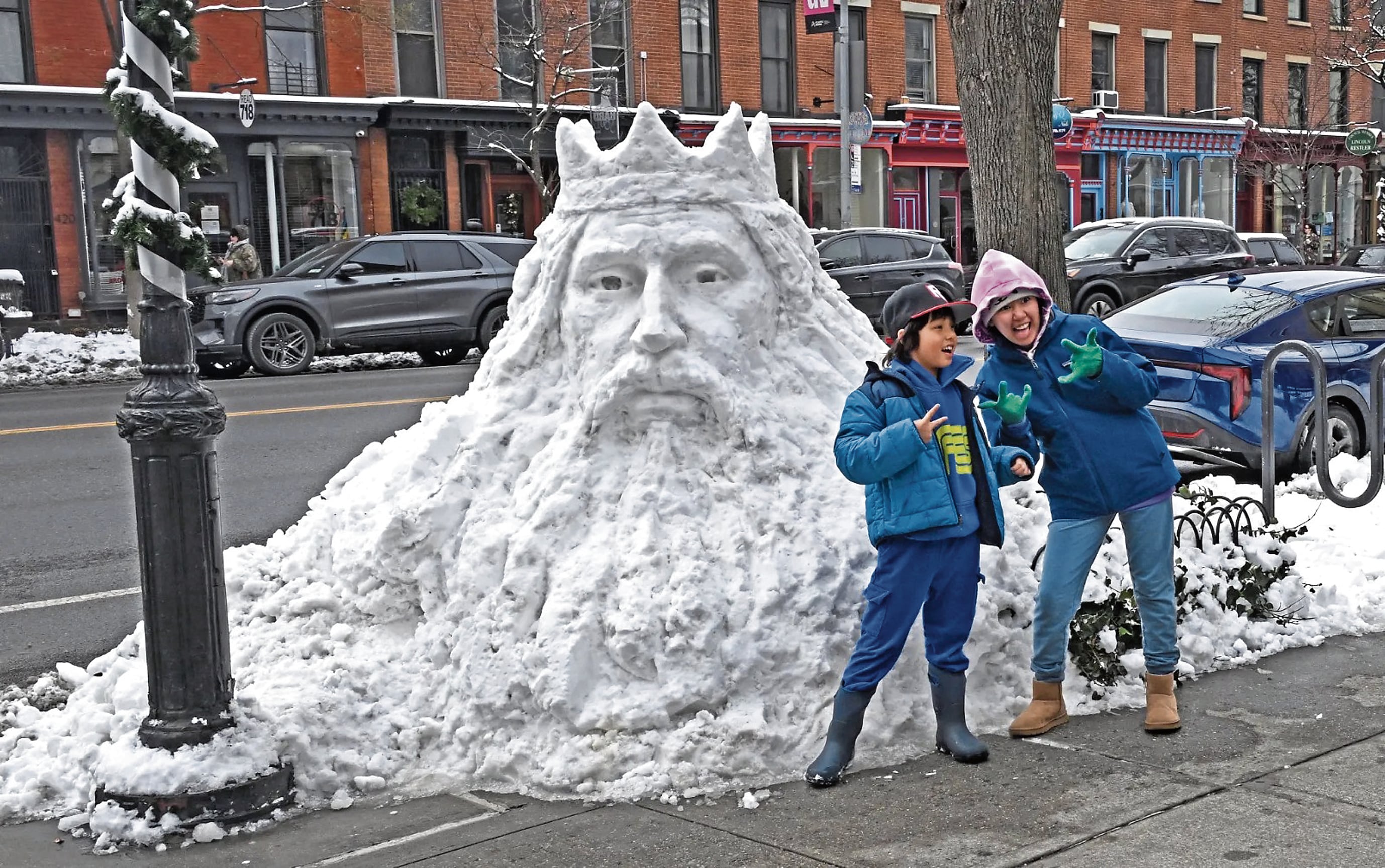 Niños se divierten junto a obra de arte de nieve, en Nueva York.