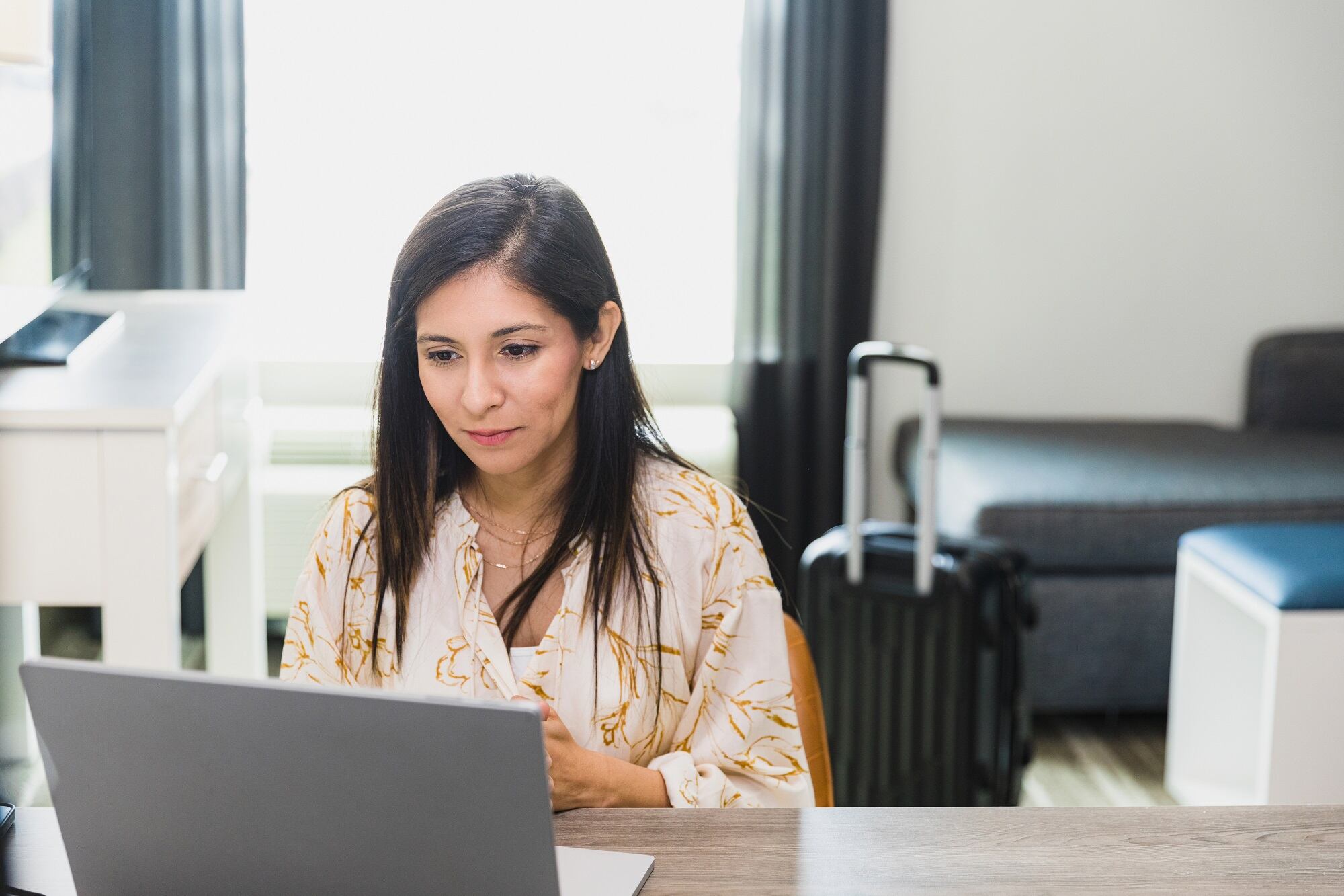 A confident businesswoman participates in a video conference in her hotel room during a business trip.