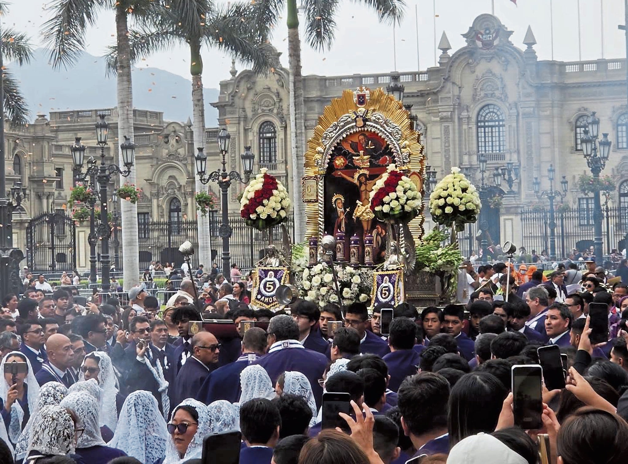 Jóvenes cargan el anda del Señor de los Milagros por la Plaza de Armas de Lima.