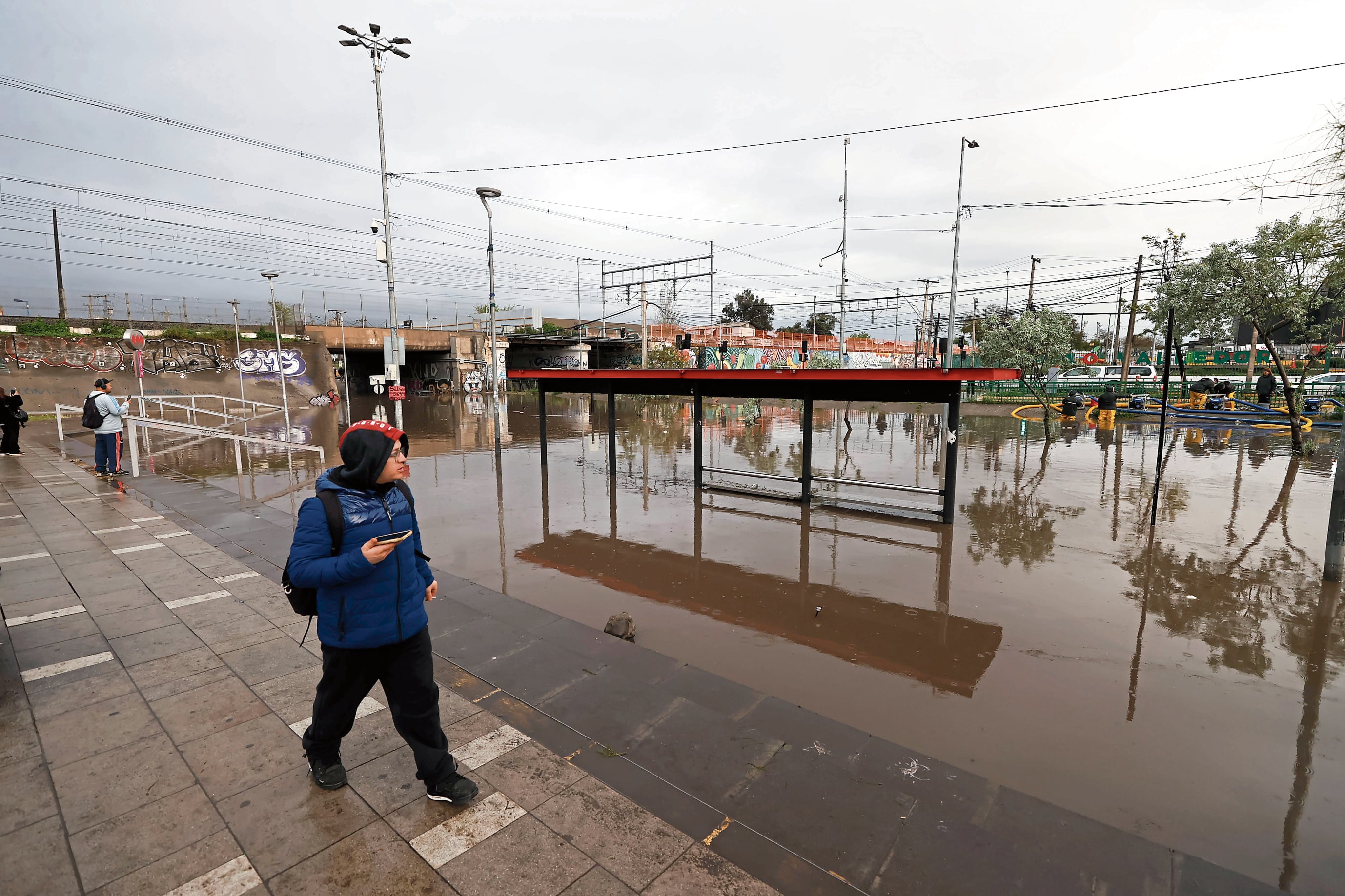 Chile soporta los embates de la naturaleza debido al fenómeno de El Niño. En la foto, una persona camina frente a una calle inundada, en la comuna de Pedro Aguirre Cerda, en Santiago de Chile. EFE/ Elvis González