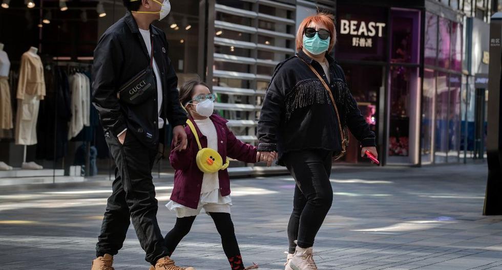 En esta imagen, tomada ayer, se aprecia a personas que usan mascarillas como medida preventiva contra el coronavirus caminando afuera de un centro comercial en Beijing. (AFP)