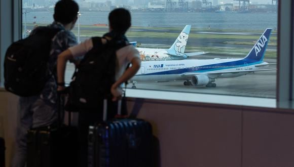 Los pasajeros miran un avión de All Nippon Airways (ANA) estacionado en la pista del aeropuerto de Haneda en Tokio el 30 de abril de 2021. (Foto: Yuki IWAMURA / AFP)